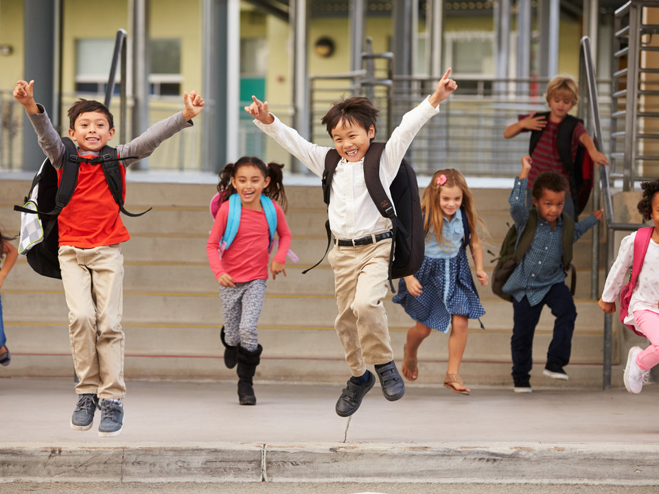 Photograph of running towards the camera in front of a school.